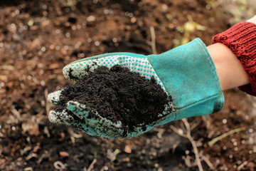 Woman holding black soil outdoors