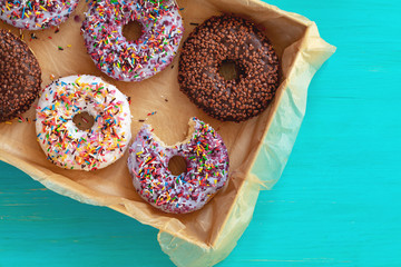 Delicious glazed donuts in box on turquoise blue surface