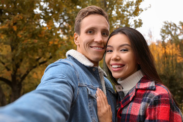 Happy loving couple taking selfie in  autumn park