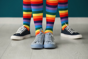 Legs of young lesbian couple in rainbow stockings standing against color wall