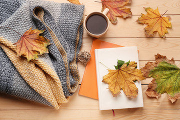 Composition with cup of delicious mulled wine, warm plaid, books and autumn leaves on wooden background