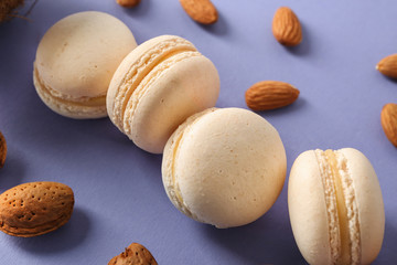 Tasty macaroons with nuts on color background, closeup