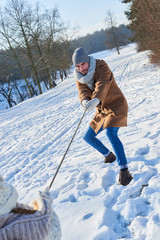 Mann beim tauziehen mit Kind im Winter