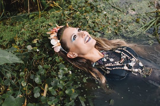 Portrait of a boho woman lying in lake, Russia