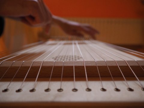 Sound healing therapy instrument Monochord, close up, with man hand playing on it.