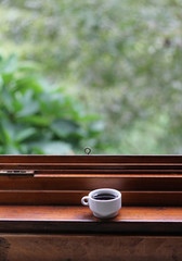Taza de café en ventana con fondo de árboles