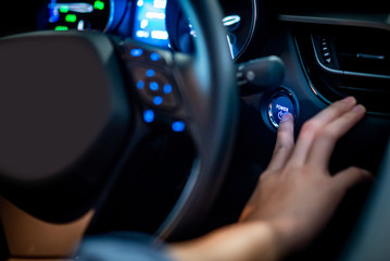 Male driver pushing car engine start-stop button or power ignition button by steering wheel in...