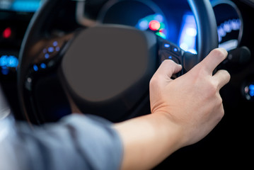 Male driver holding steering wheel in modern car with blue light dashboard on the console. Auto transport technology for automobile industry concept
