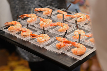 waiter with a tray serving fried shrimp appetizers during a festive dinner