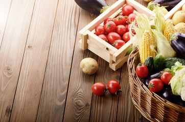 Basket of Organic Vegetable Food Ingredients and crates of potatoes and tomatoes on wood background