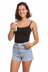Young happy Caucasian teenage girl smiling and holding glass of 