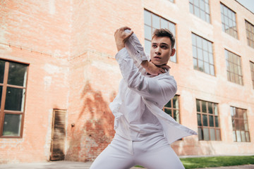 Fototapeta na wymiar young man in white clothes dancing on city street