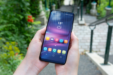 Woman holding modern smartphone in a park mockup