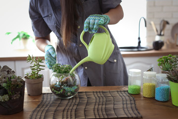 Woman watering glass terrarium, creativity plants