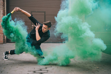 handsome young male dancer in green smoke on street