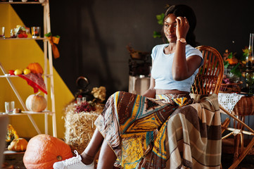 African american girl sitting at rocking chair against autumn mood decoration. Fall in Africa.
