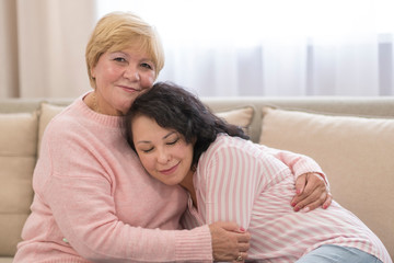 Joyful smiling woman and her adult daughter resting at home