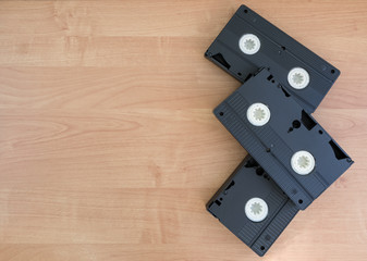 2 black VHS with white spoons lyying on a beige wooden background with copy space.