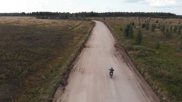 Aerial view, Camera follows of the motocross rider riding on his motorcycle on the off-road track