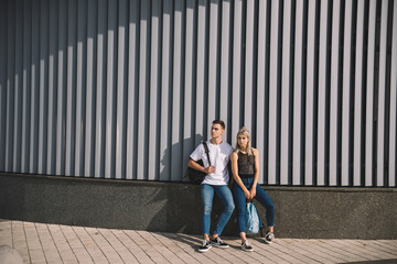 beautiful young couple with backpacks standing together on street