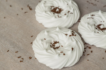 homemade white air meringues and chocolate confectionery decorations on  on parchment paper.