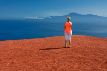 Kobieta stojąca na czerwonej skale, patrząca na ocean wulkan Teide na Teneryfie, widok z Mirador de Abrante La Gomera © Agnieszka