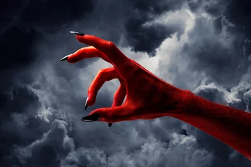 Fotobehang Halloween red devil monster hand with black fingernails against a dark sky © ink drop