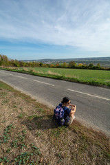 Woman sitting along country road - 229716372