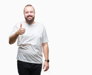 Young caucasian hipster man wearing casual t-shirt over isolated background doing happy thumbs up gesture with hand. Approving expression looking at the camera with showing success.