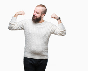 Fototapeta premium Young caucasian hipster man wearing winter sweater over isolated background showing arms muscles smiling proud. Fitness concept.