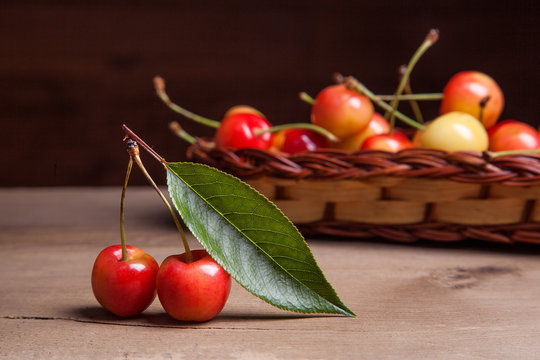 Yellow sweet cherry in basket on wooden background.