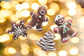 Gingerbread cookies on the background of golden Christmas lights. The concept of celebrating Christmas and New Year.