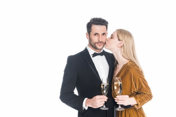 portrait of stylish woman kissing boyfriend with glass of champagne isolated on white