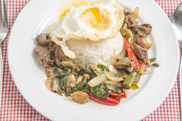 Fried rice with basil leaves and red cloth on the table.Ngredients of Basil Fried Chicken and fried egg.Do not focus on objects.