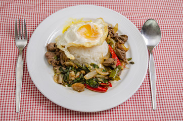 Fried rice with basil leaves and red cloth on the table.Ngredients of Basil Fried Chicken and fried egg.Do not focus on objects.