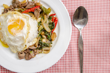 Fried rice with basil leaves and red cloth on the table.Ngredients of Basil Fried Chicken and fried egg.Do not focus on objects.