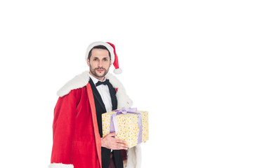 portrait of stylish man in santa claus costume holding wrapped present isolated on white
