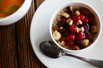 healthy breakfast: oatmeal with dried fruits, nuts and honey and a cup of hot citrus tea