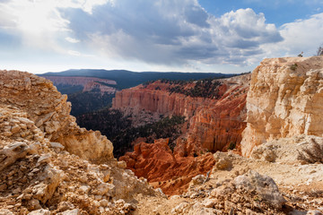 Obraz premium Bryce Canyon National Park high view point vast forest and mountains landscape. The red sandstone rock formations on the foreground and clouds in the sky