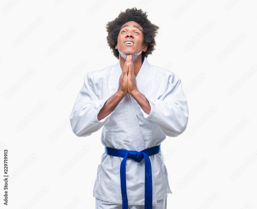 Canvas Prints Afro american man wearing karate kimono over isolated background begging and praying with hands together with hope expression on face very emotional and worried. Asking for forgiveness