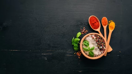 Rolgordijnen Spices and herbs on a wooden board. Pepper, salt, paprika, basil, turmeric. On a black wooden chalkboard. Top view. Free copy space. © Yaruniv-Studio
