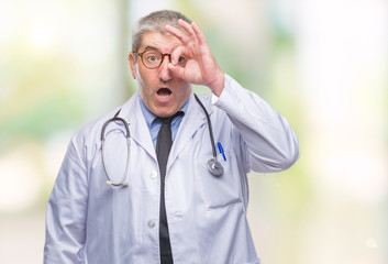 Handsome senior doctor man over isolated background doing ok gesture shocked with surprised face, eye looking through fingers. Unbelieving expression.