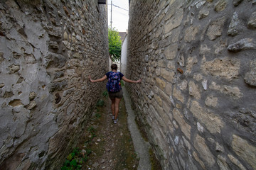 Person walking through alley in French village - 229723512