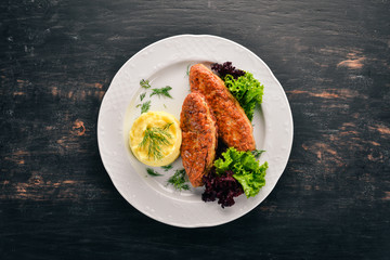 Cutlets of meat with mashed potatoes on a plate. On the old wooden background. Free space for text. Top view.