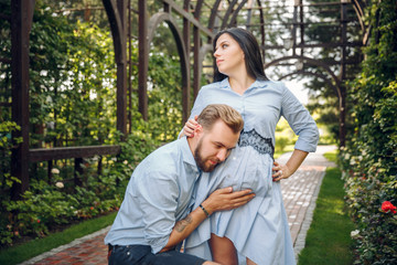 Fototapeta premium couple pregnant in the spring in the flowered garden, a man listening to stomach of pregnant