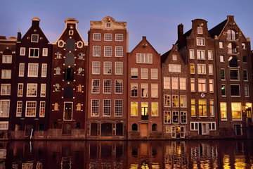 Fototapeta na wymiar Famous dancing houses of the Damrak canal in Amsterdam on dusk