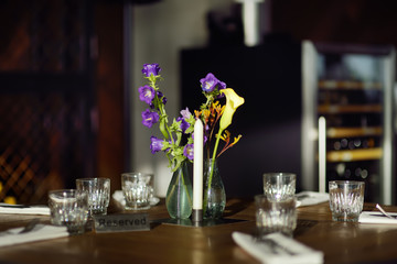 Reserved table in a cafe or restaurant with flowers in a vase and a candle.