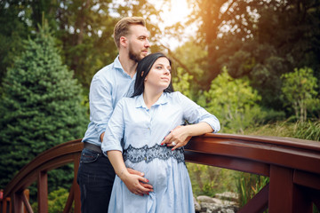 Romantic portrait of young smiling happy couple of lovely future parents during sunset on nature apple tree background in the city park. Pregnancy pregnant future mother photoshoot.