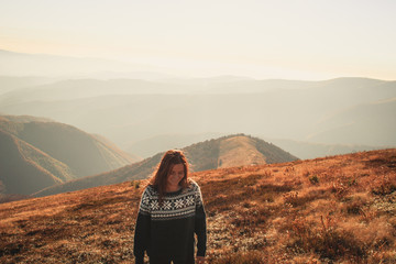 A girl in a blue sweater with a pattern. Ukrainian Carpathians in autumn. Warm colored green...