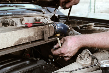 The bright man repairs the car. Hands in oil. Engine repair and fuel system. Masters works. Outdoor hood machine.Mechanic